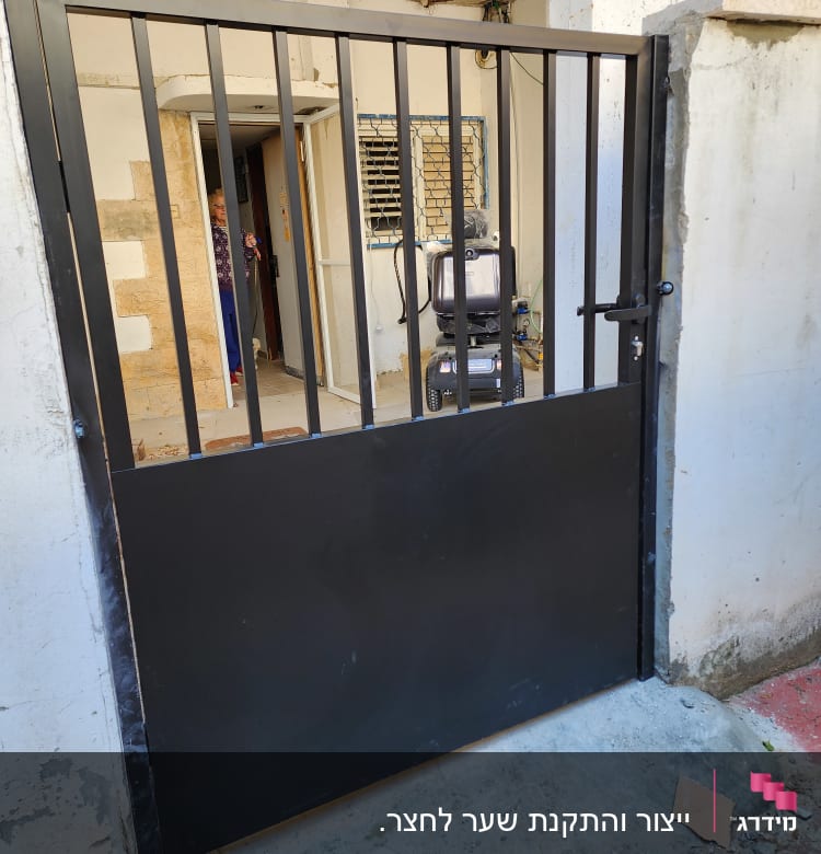 שער מתכת שחור עם סורגים אנכיים ודלת נעולה